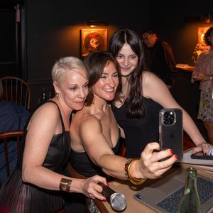 Three women pose for a selfie at a dark bar venue during a social event.