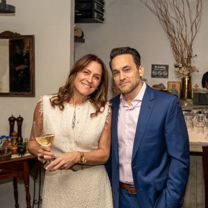 A man in a blue suit and woman in white dress pose together at an elegant indoor social event.