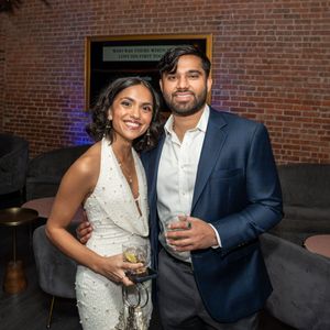 Smiling couple posing together with drinks at a modern lounge party.