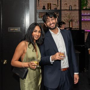 Couple smiling and holding drinks at a stylish upscale bar event.