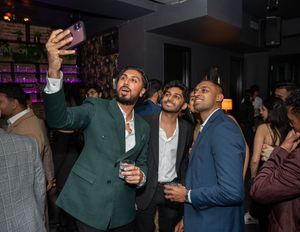 Three men taking a group selfie at a vibrant nightclub event.