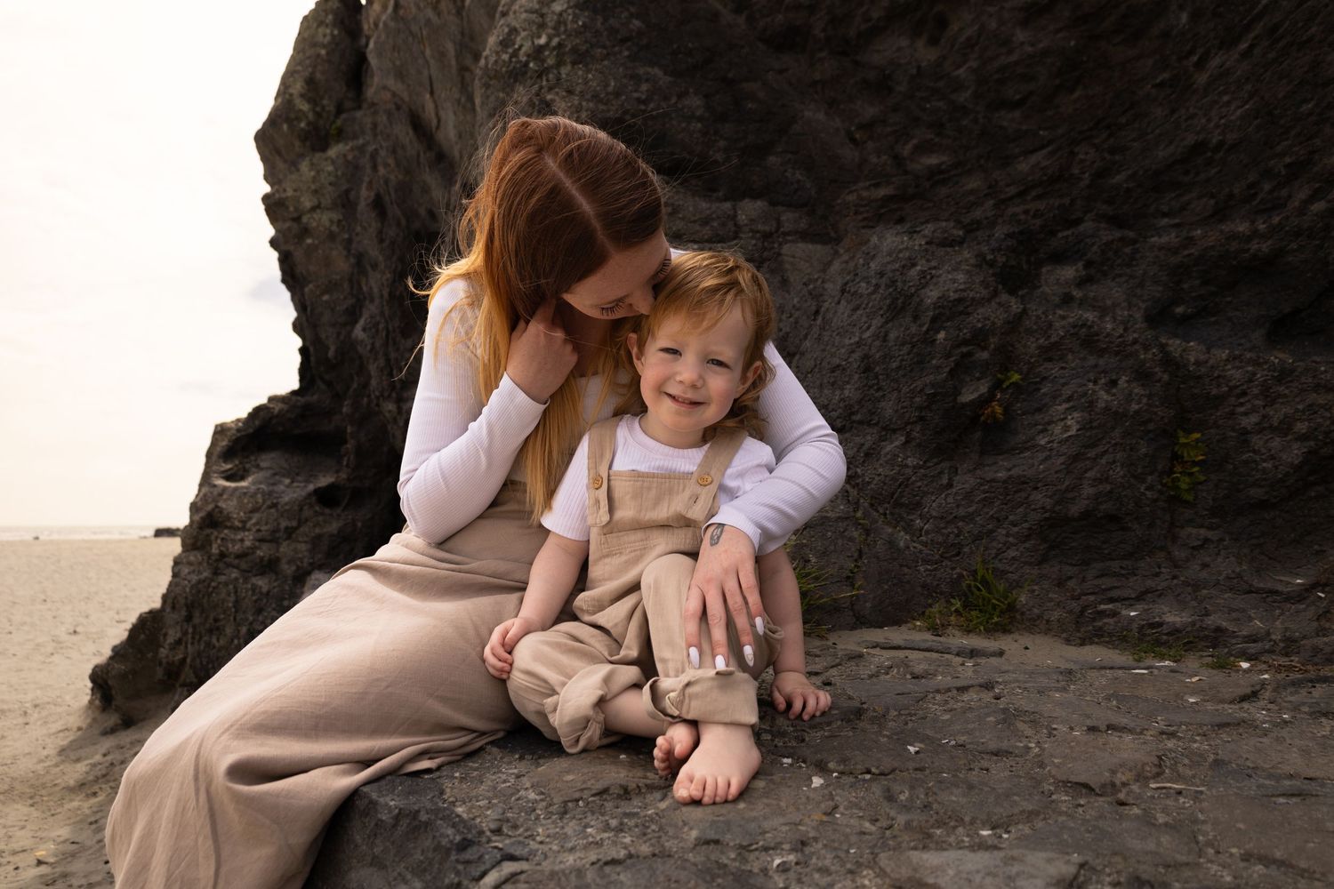 Motherhood session at Sumner beach. Mum holding onto her son kissing his forehead