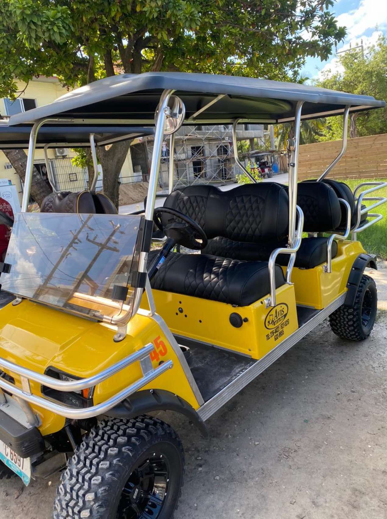 A bright yellow lifted golf cart with custom wheels and off-road tires shown from multiple angles under a carport.