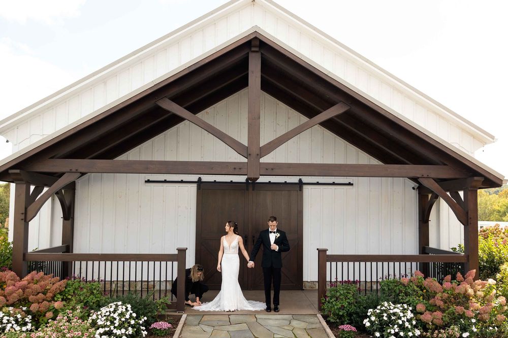 A long covered walkway with white posts and wooden beams connects multiple buildings on a sunny day.
