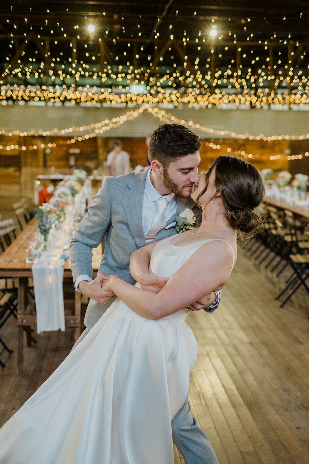 A romantic dance moment at a wedding reception under twinkling string lights in an elegant venue.