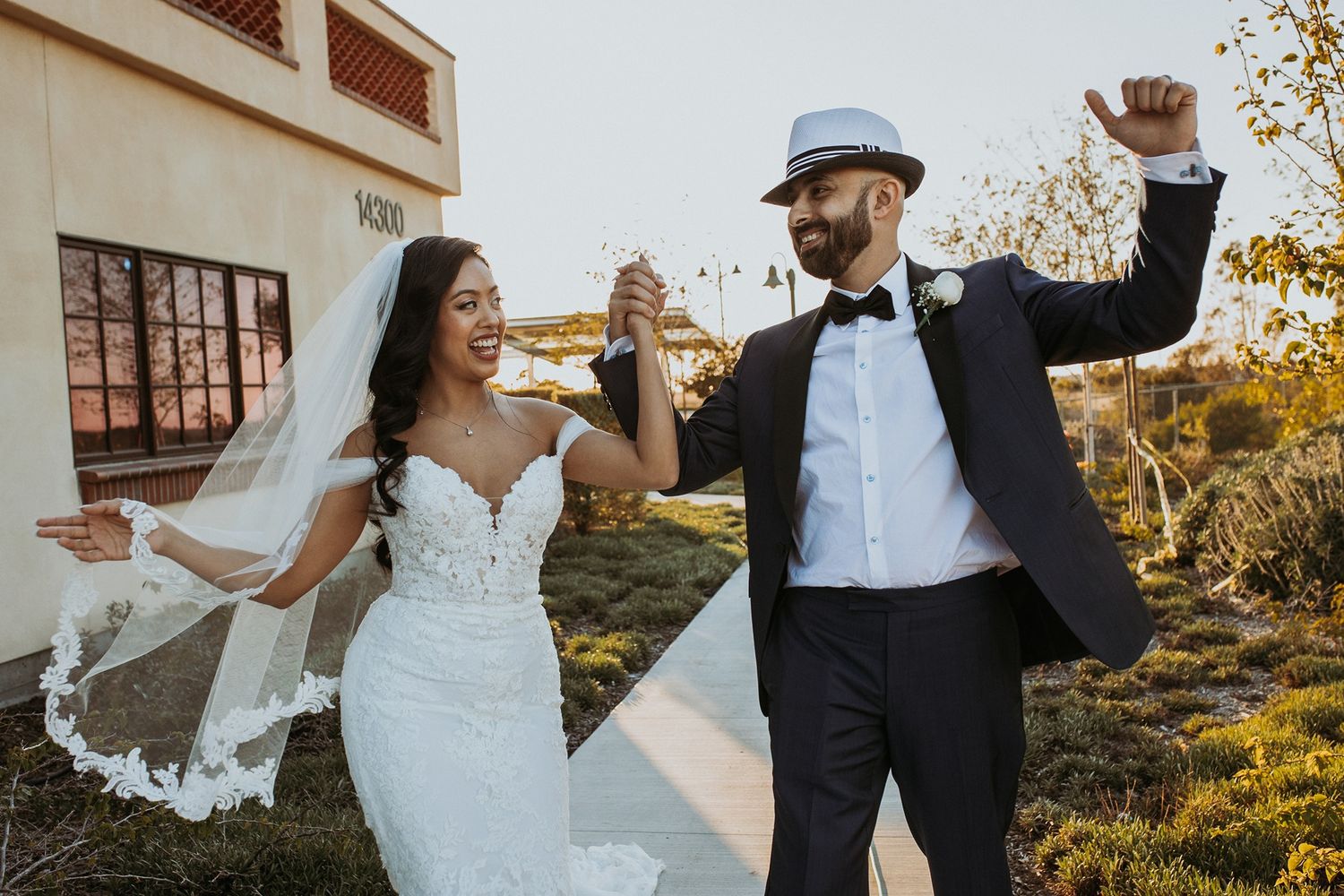 Elegant couple in wedding attire dancing together during golden hour after the ceremony.