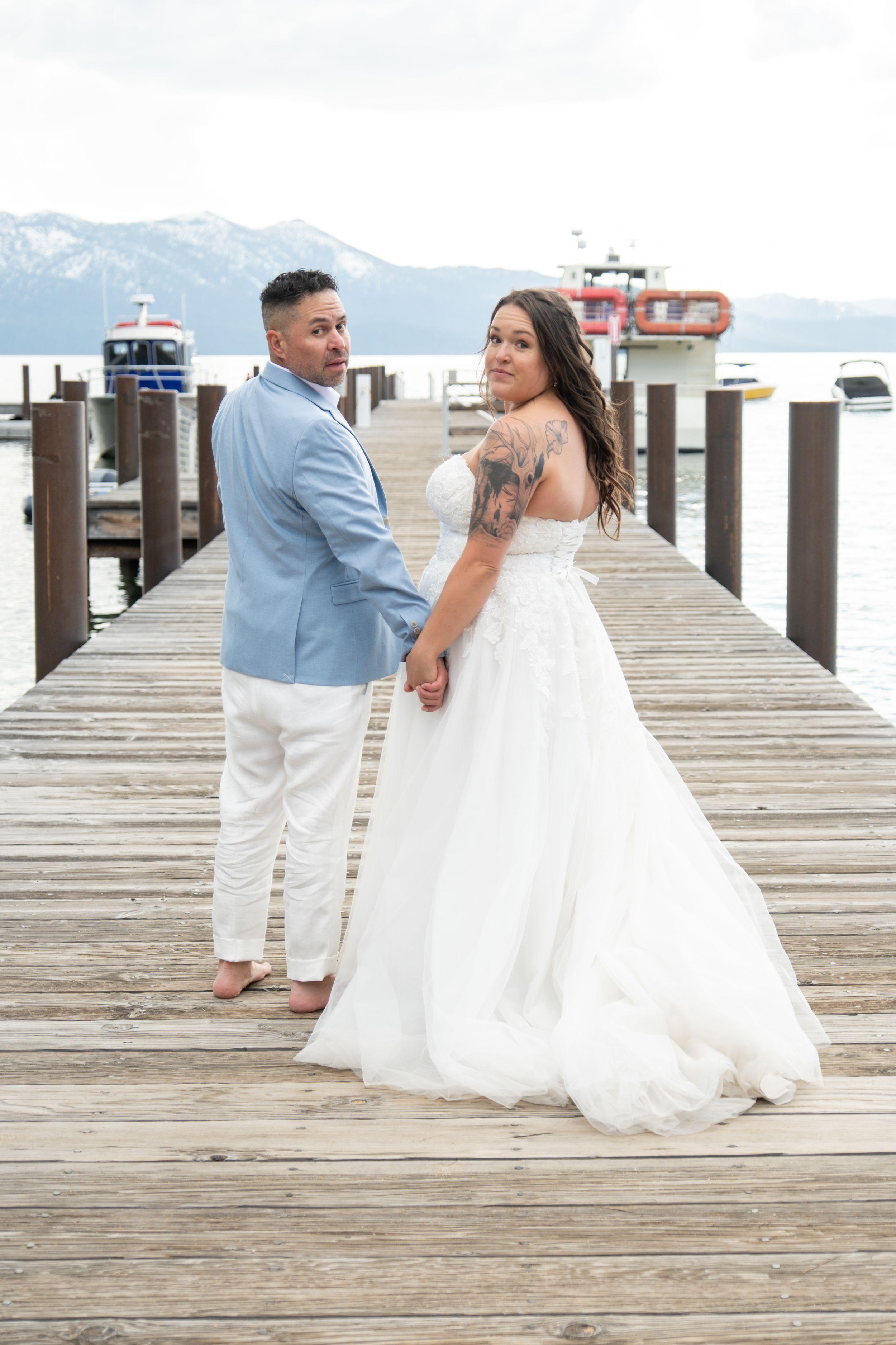 A romantic wedding photo sequence on a wooden pier with mountains and a lighthouse in the background.