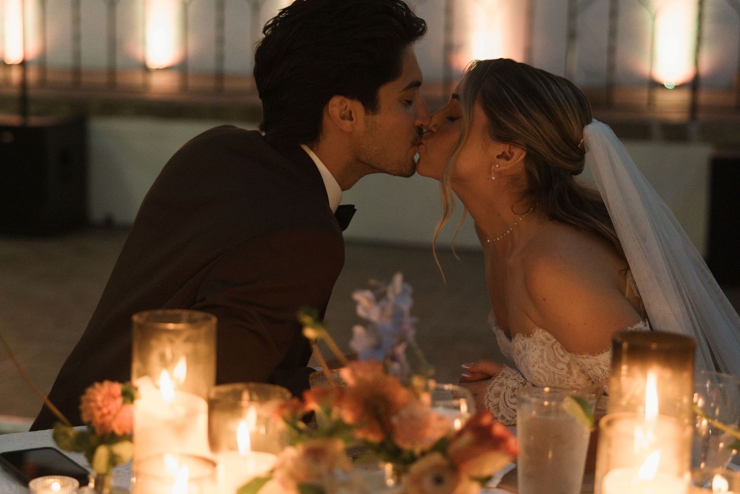 Romantic candlelit wedding reception at a Santa Barbara restaurant with a couple kissing in warm evening light