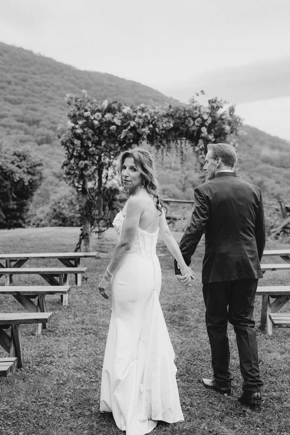 A sequence of black and white photos showing a couple walking together in a scenic mountain setting with benches.
