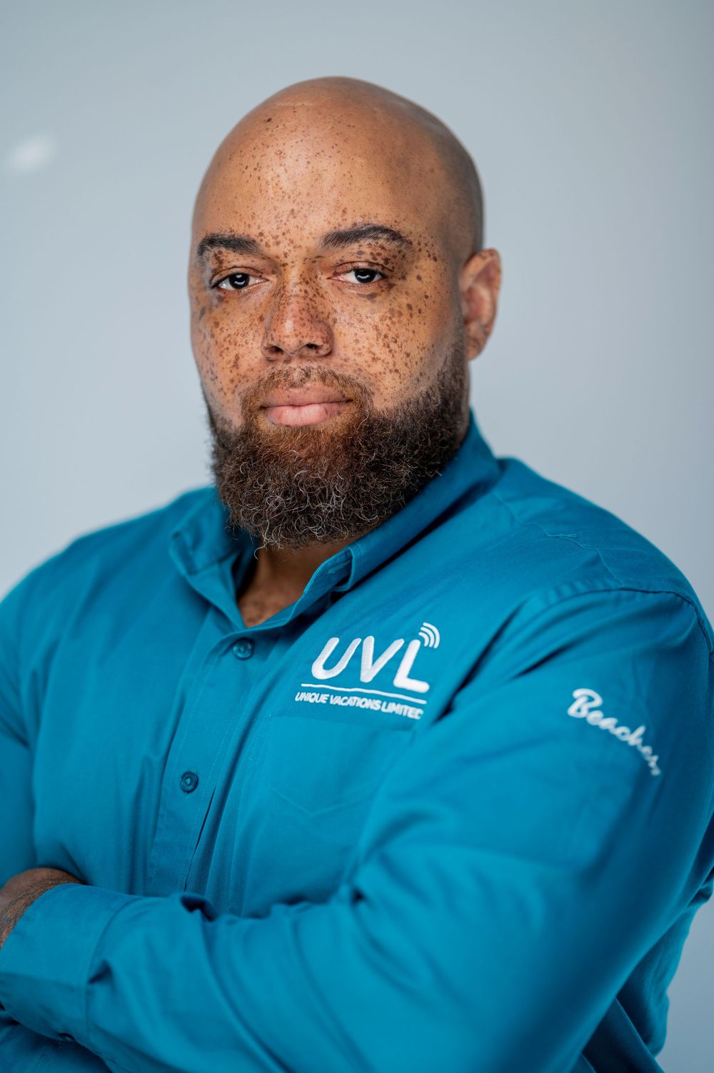 Professional headshot of someone wearing a blue UVL branded polo shirt against a light gray background.