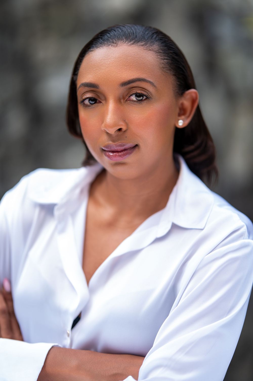 Professional headshot portrait of a person in a crisp white collared shirt against a soft blurred background.