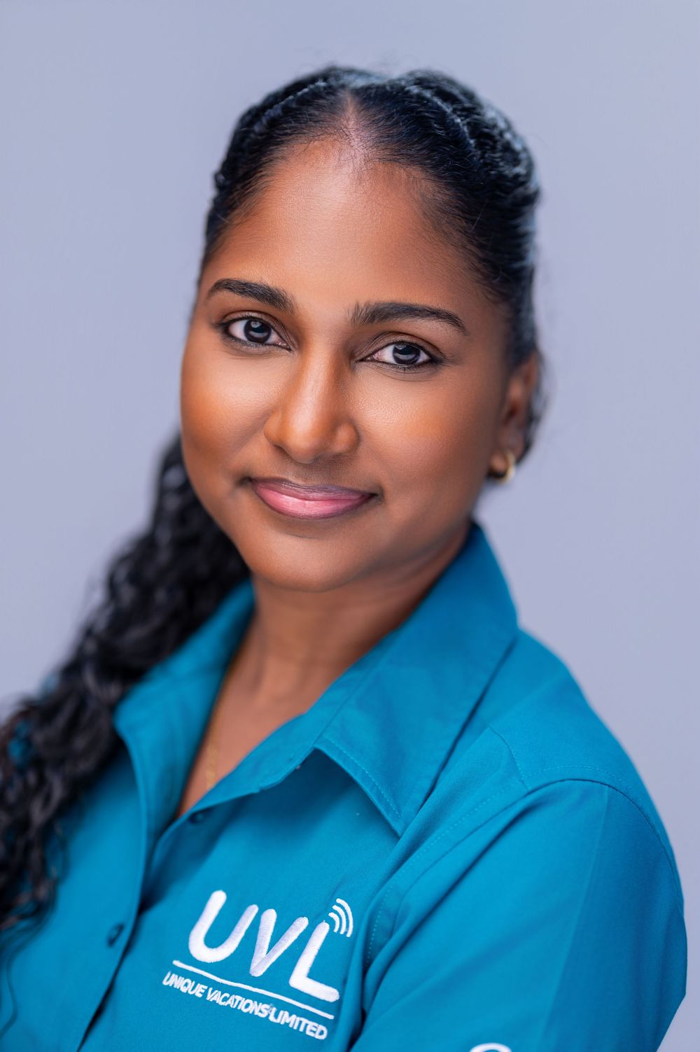 Professional headshot of someone in a bright turquoise collared shirt against a light gray background.
