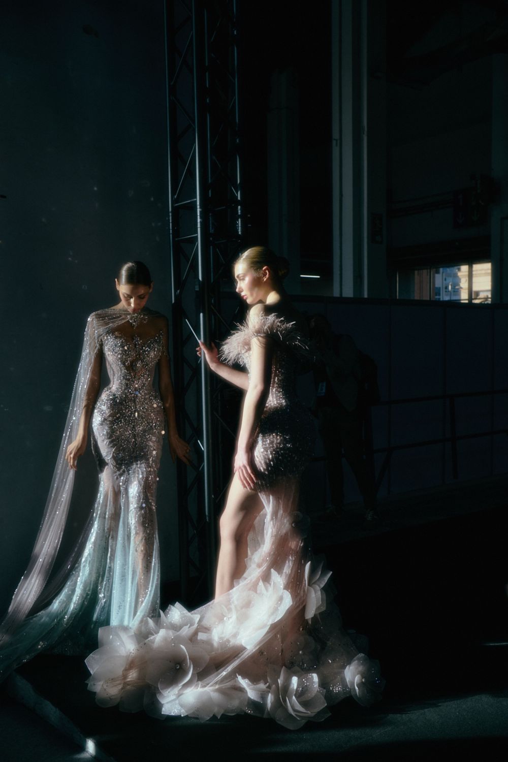 Sheer embellished gowns with flowing capes photographed in dramatic low lighting.