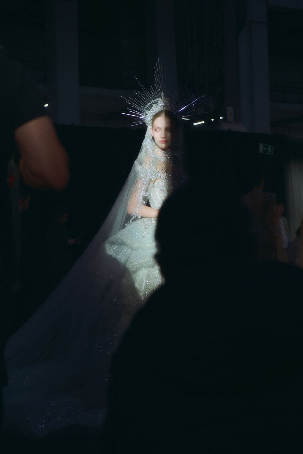 Models showcase elegant white wedding gowns on a dark runway during a bridal fashion show.