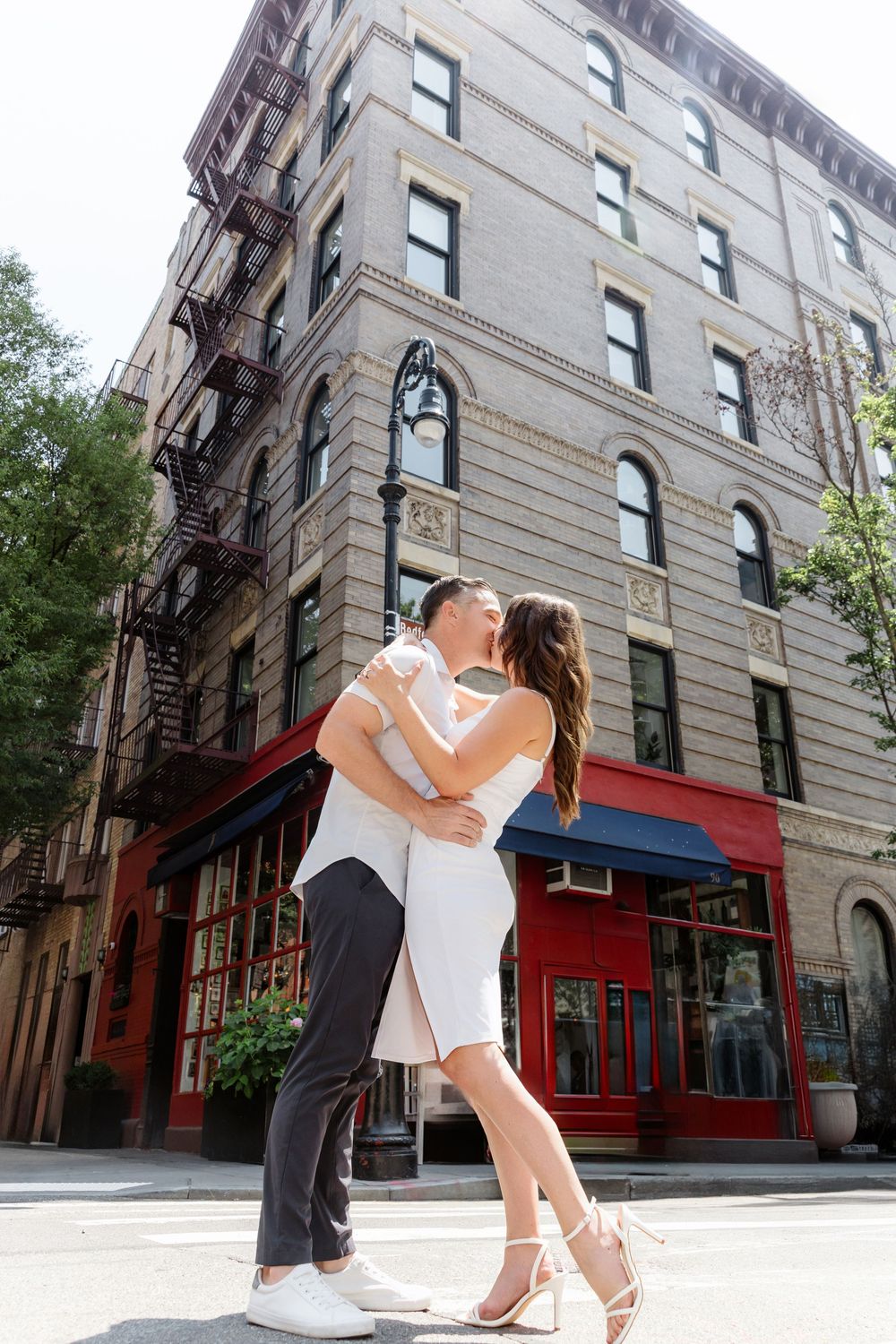 Couple dancing and dipping in front of a historic brick building with classic New York architecture.