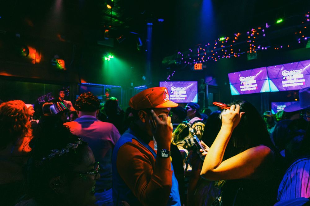 Silhouettes of party-goers against vibrant blue and green nightclub lighting creating a dynamic club scene.
