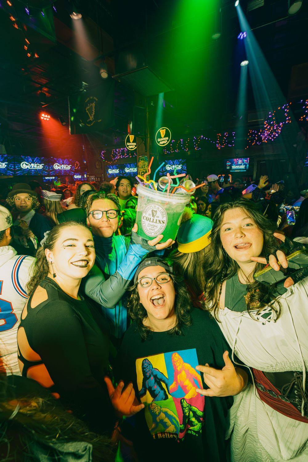 Energetic crowd enjoying a nightclub party under vibrant green and blue lighting effects.