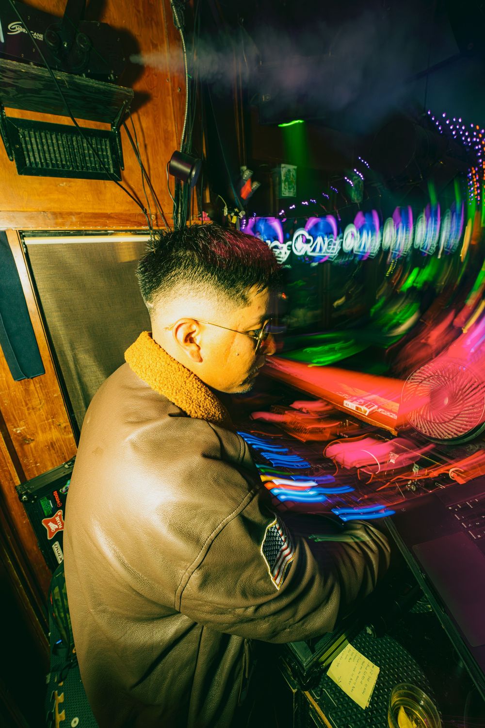 A DJ performs at a nightclub with colorful lighting and motion blur effects creating an energetic atmosphere.