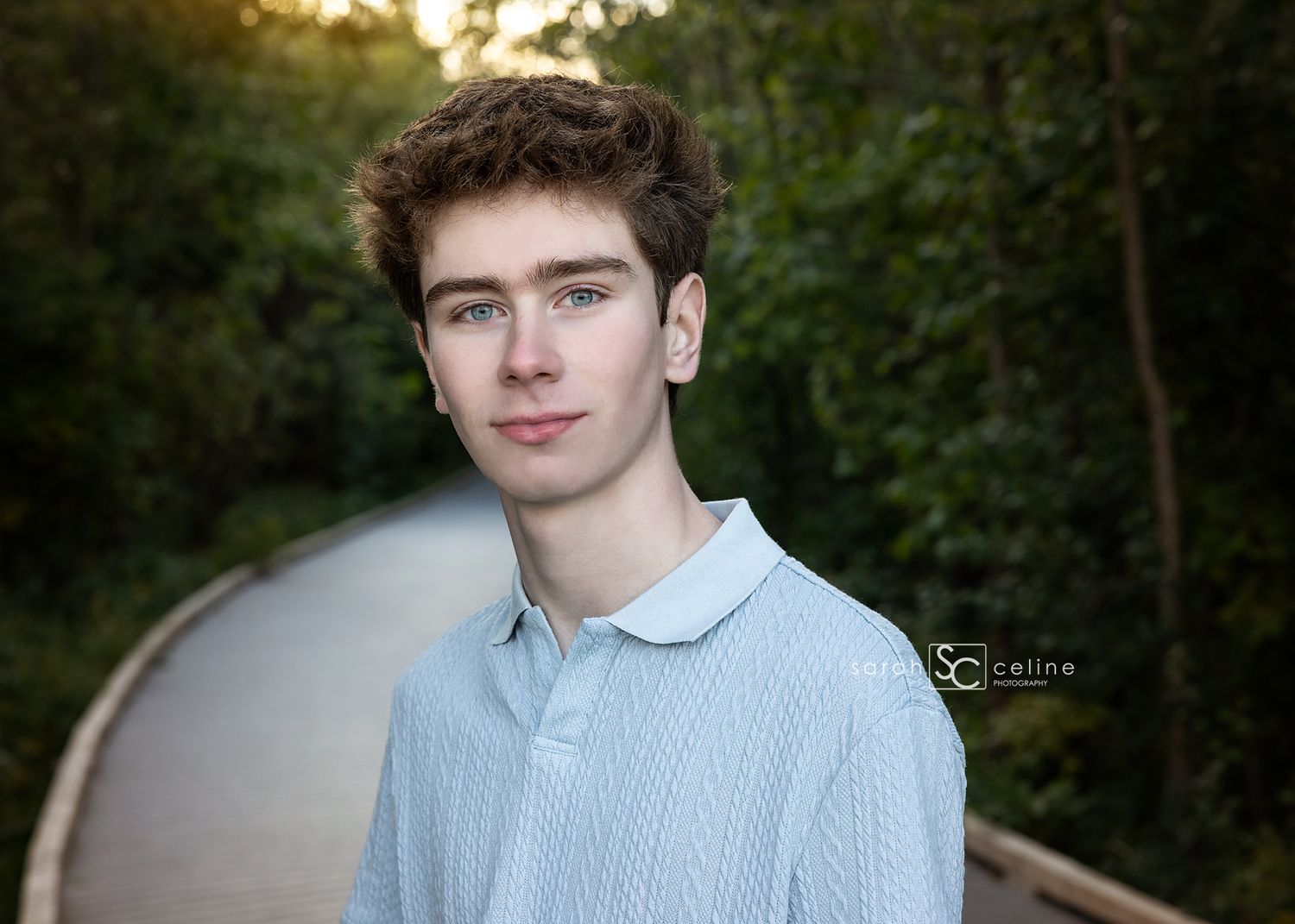 Outdoor portrait session in greenery with soft natural lighting and a light blue sweater.