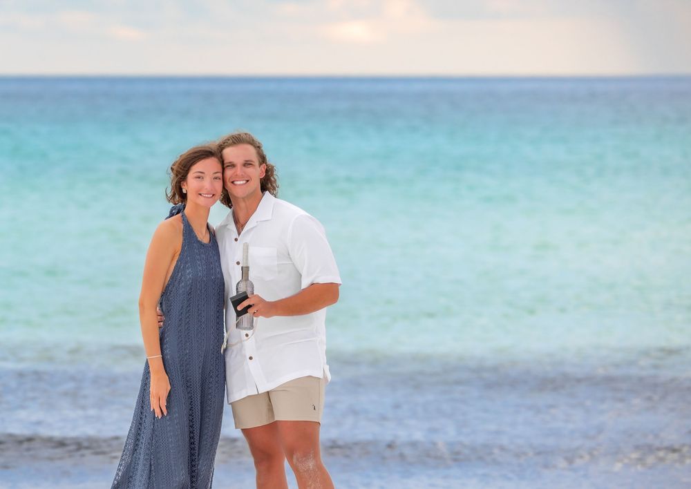 A couple embraces while walking along a beautiful turquoise beach with crystal clear water and white sand.