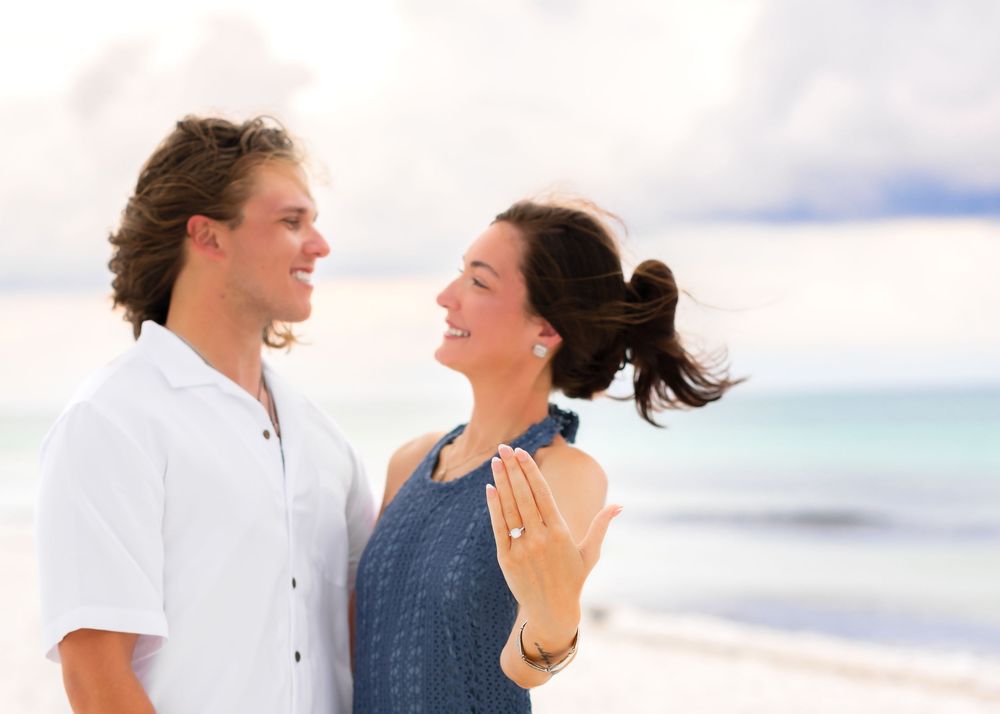 A couple in casual attire sharing an intimate moment while standing on a scenic beach.