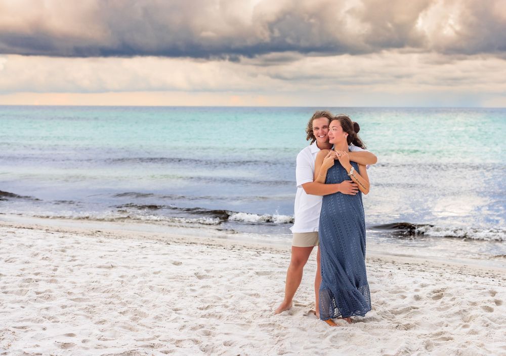 A romantic beachside photo session at sunset with waves crashing along the white sandy shoreline.