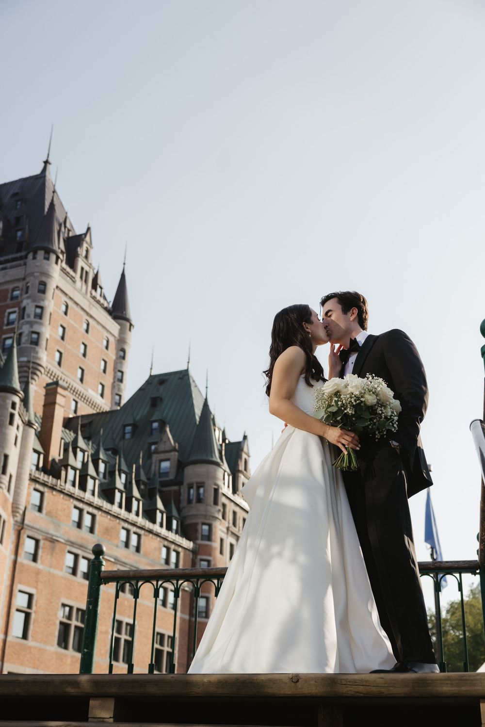 A romantic wedding moment captured outside the iconic Chateau Frontenac in Quebec City, with its grand architecture in backdrop.