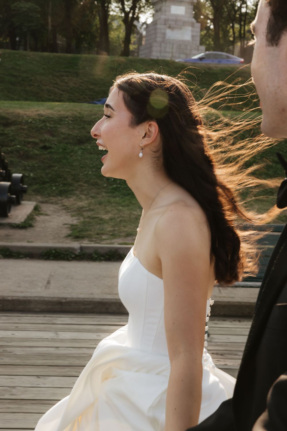 A bride laughs with pure joy in the golden sunlight, her hair swept by the wind.
