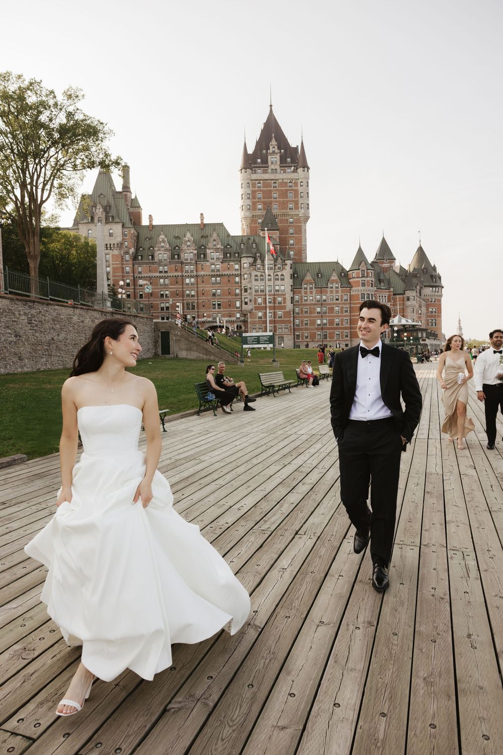 Wedding couple posing on a wooden boardwalk with the majestic Chateau Frontenac castle in the background.