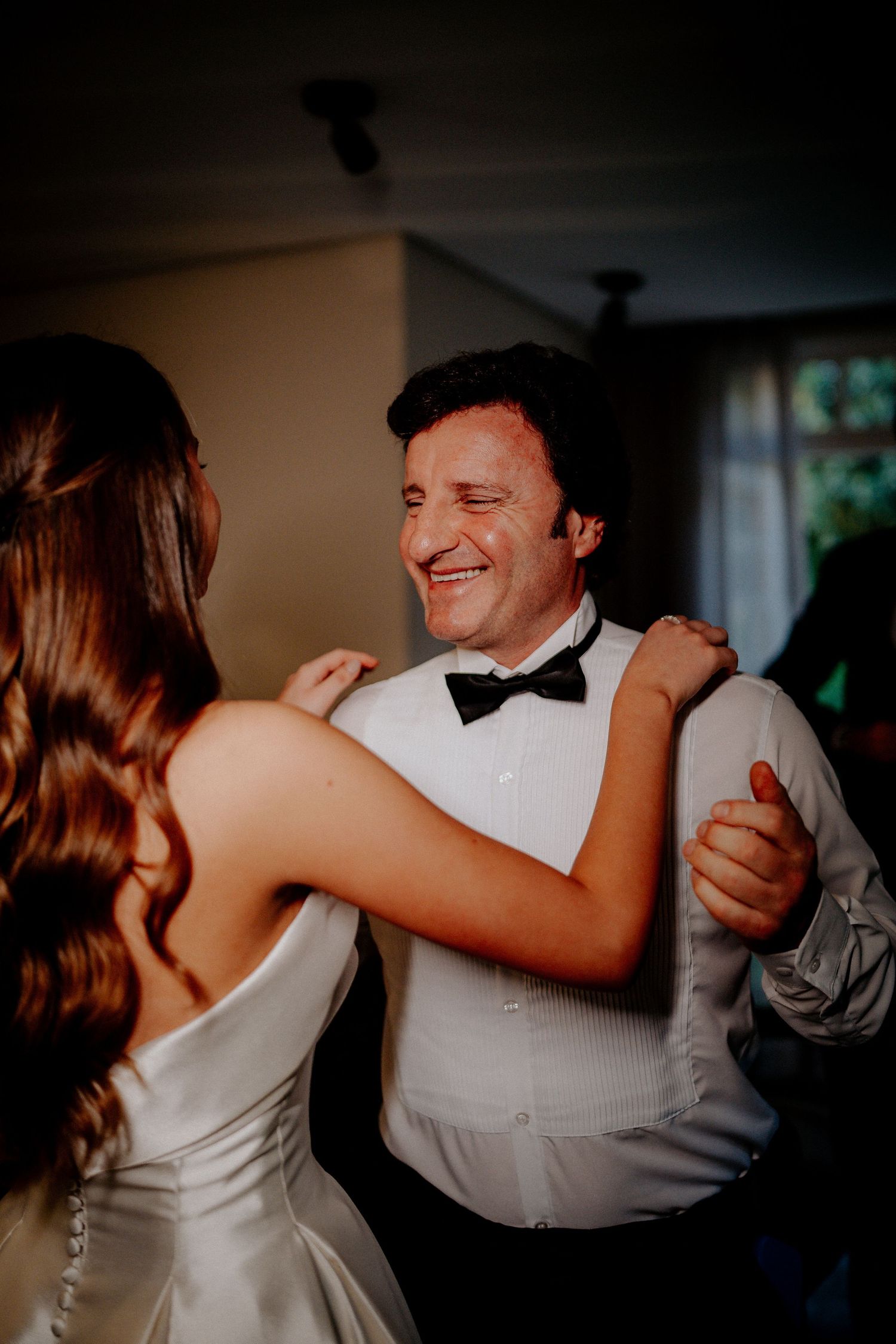 Dancing couple at wedding reception with person in white dress and partner in formal attire.