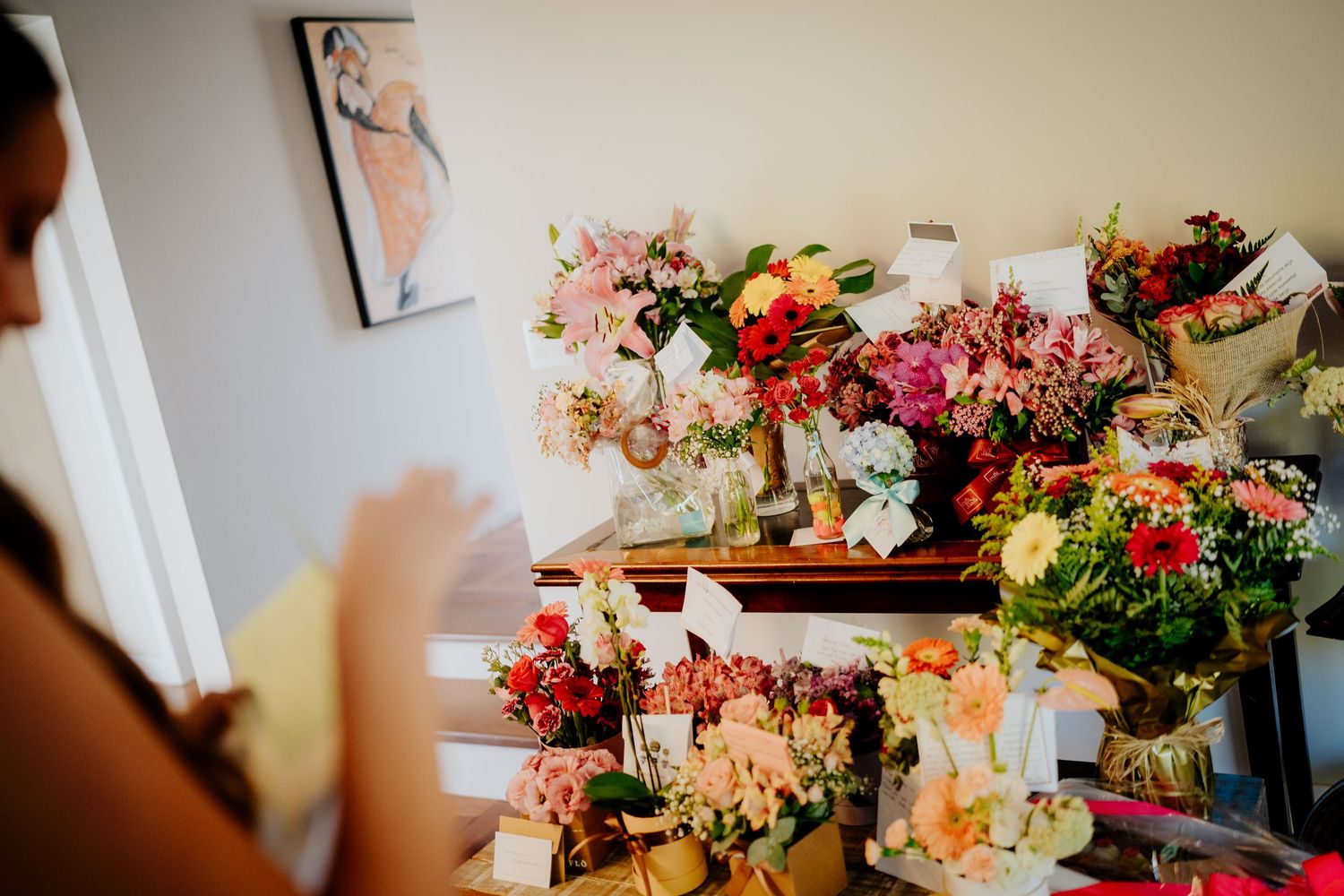 Vibrant floral arrangements with pink and red flowers displayed on wooden furniture.