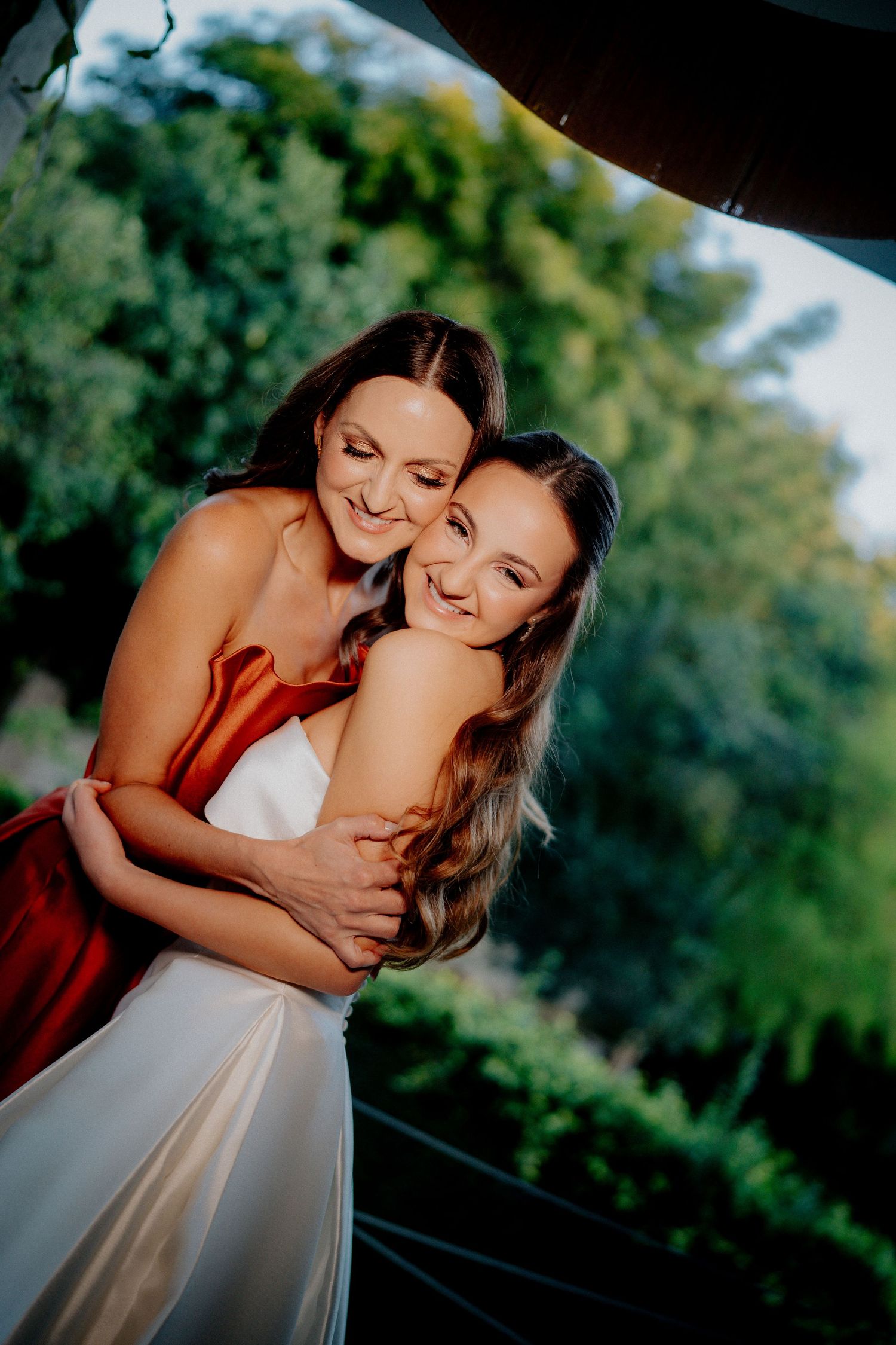 Joyful wedding moment between two people hugging outdoors with lush green background.