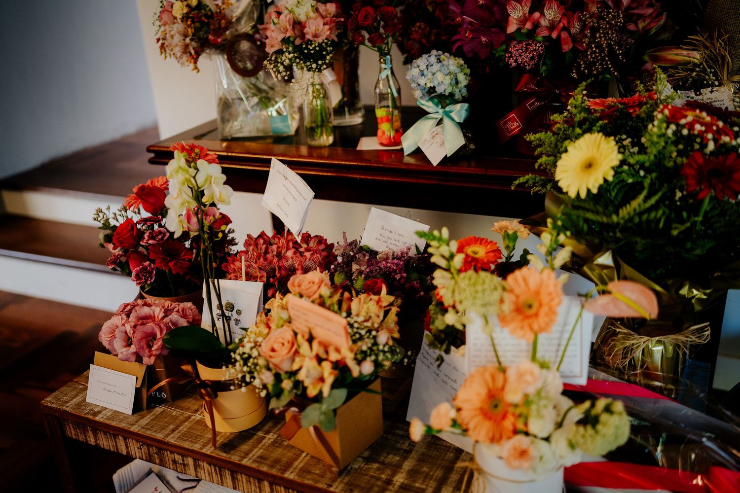 Colorful floral arrangements displayed on wooden tables with vibrant red and yellow blooms.