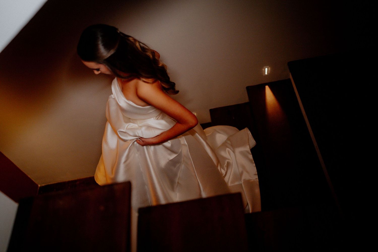 Artistic wedding photography with dramatic lighting and elegant white dress details.