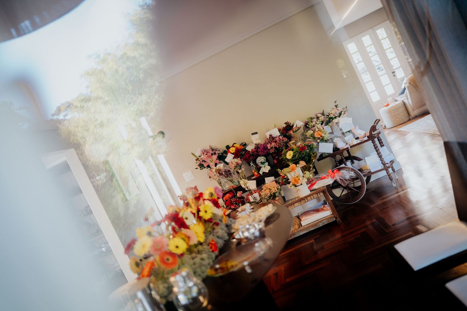 Sunlit table display of colorful wedding floral arrangements in soft focus.