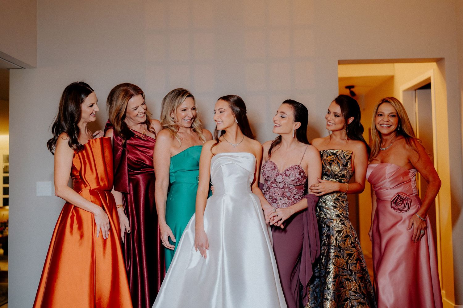 A collection of colorful bridesmaid dresses hanging in a row at a wedding preparation area.