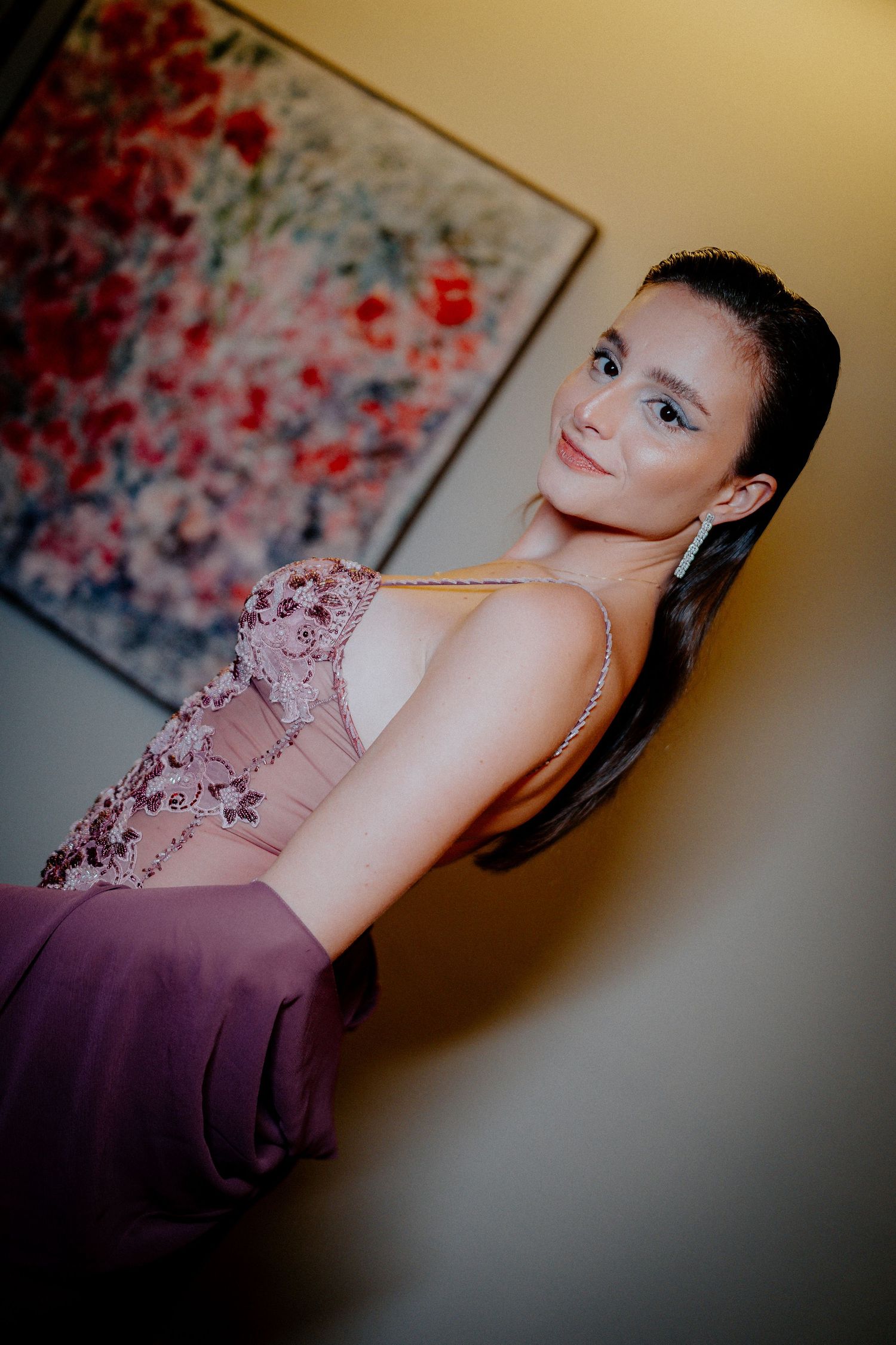 A formal portrait session featuring a purple evening gown against an artistic backdrop.
