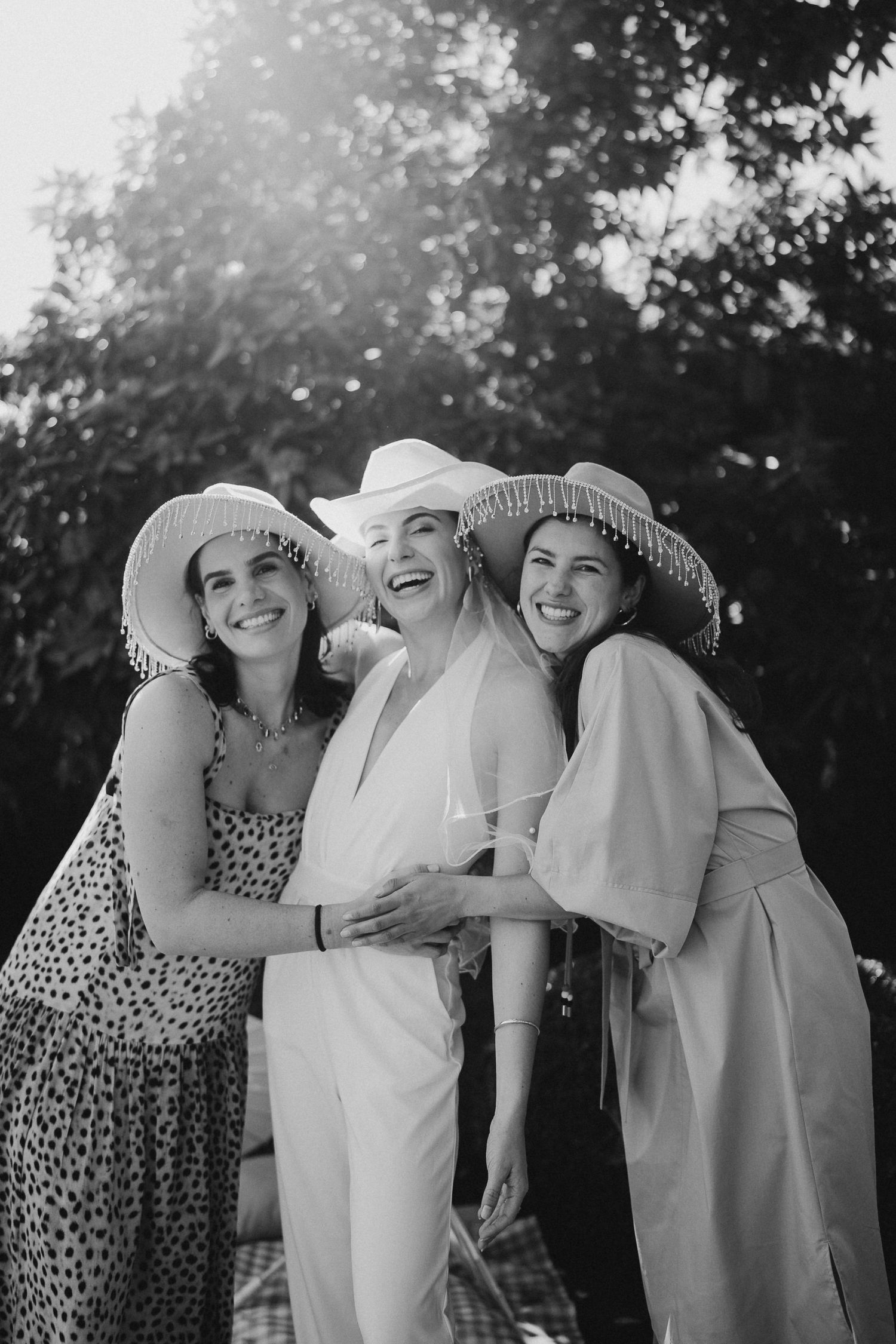 Black and white photo of three people in summer attire laughing together outdoors.