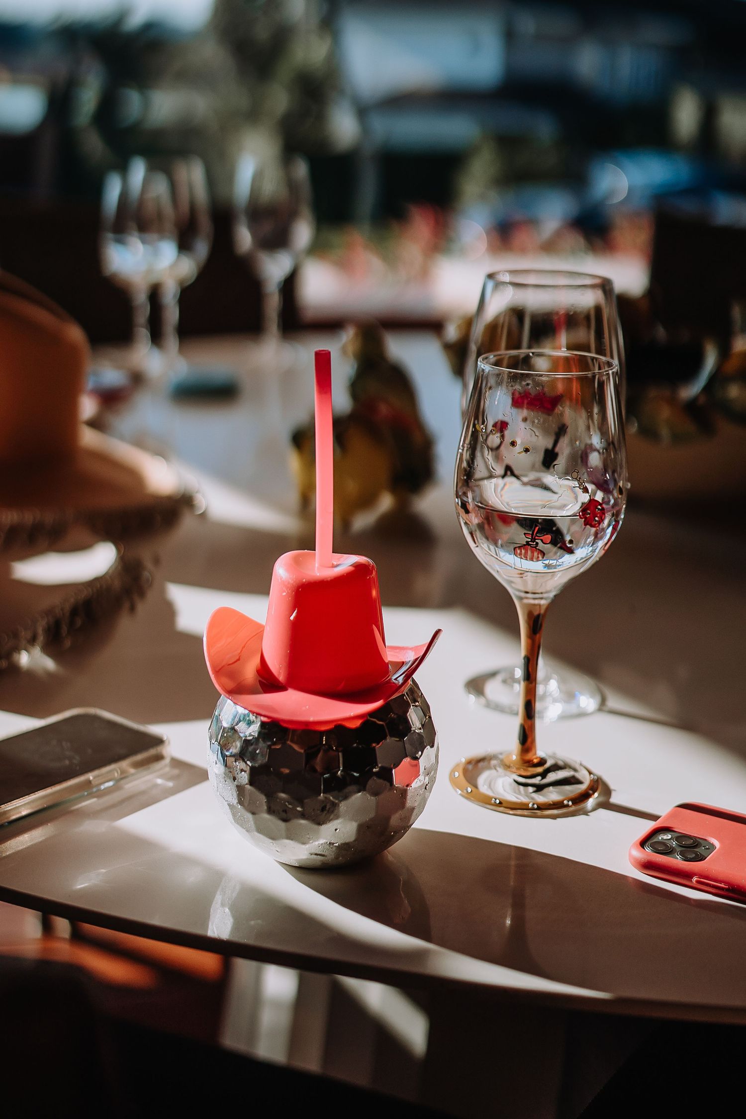 Table setting with wine glasses and red decorative elements in moody lighting.