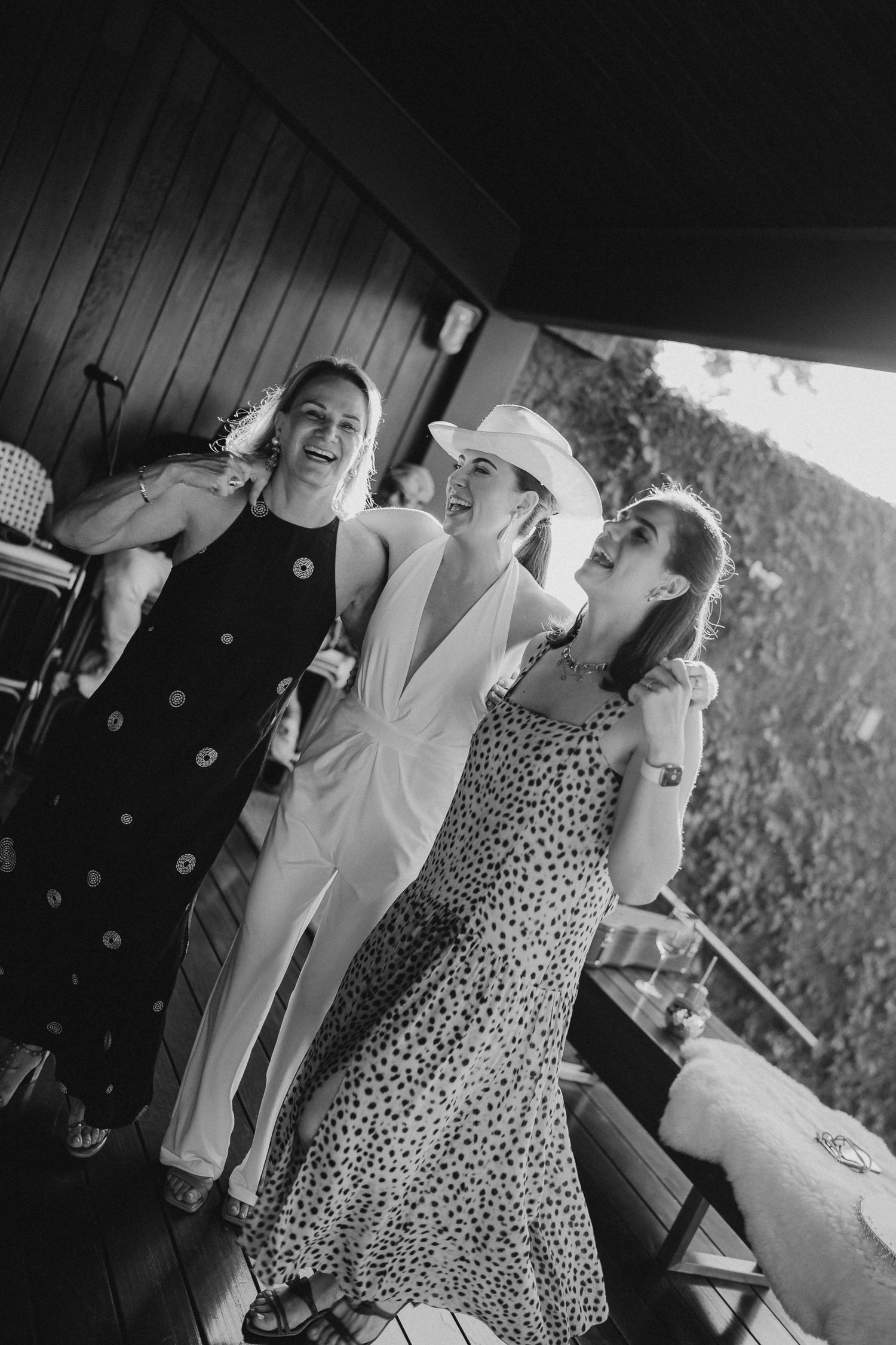 Party guests in summer dresses laughing and dancing at outdoor celebration.