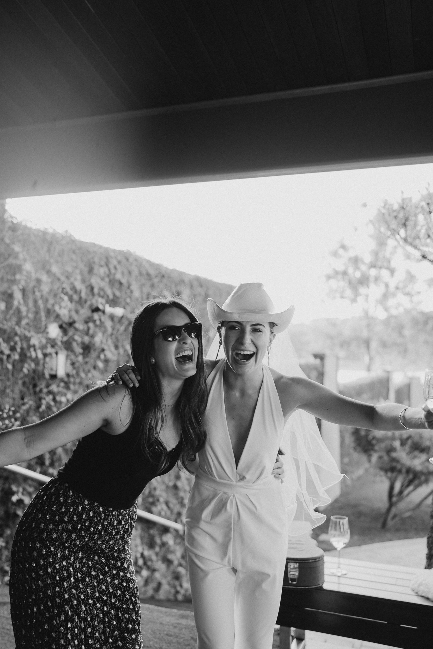 Two guests in contrasting outfits dancing and celebrating on an outdoor deck.