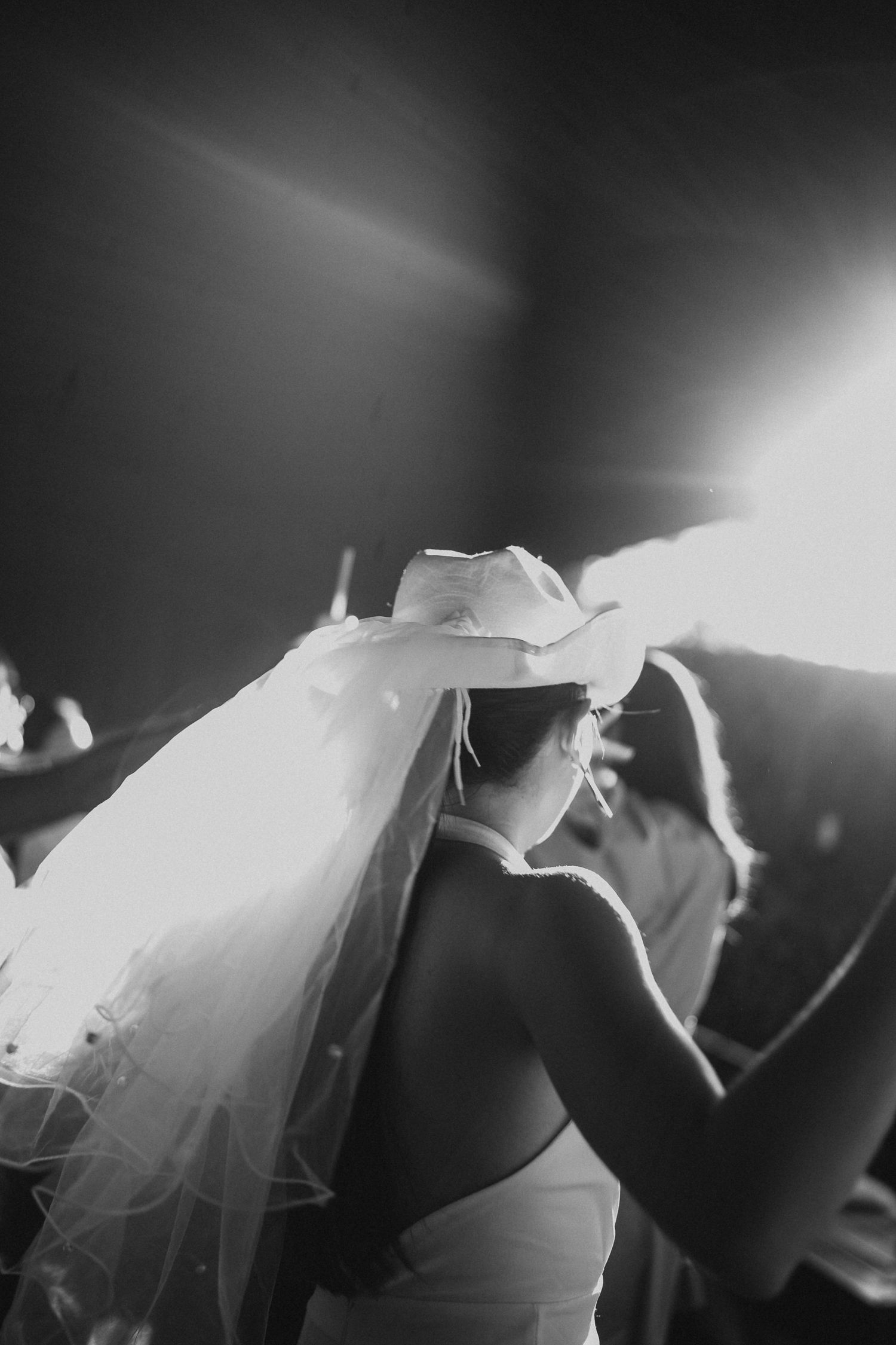 Artistic black and white photo of party guests dancing in atmospheric lighting.