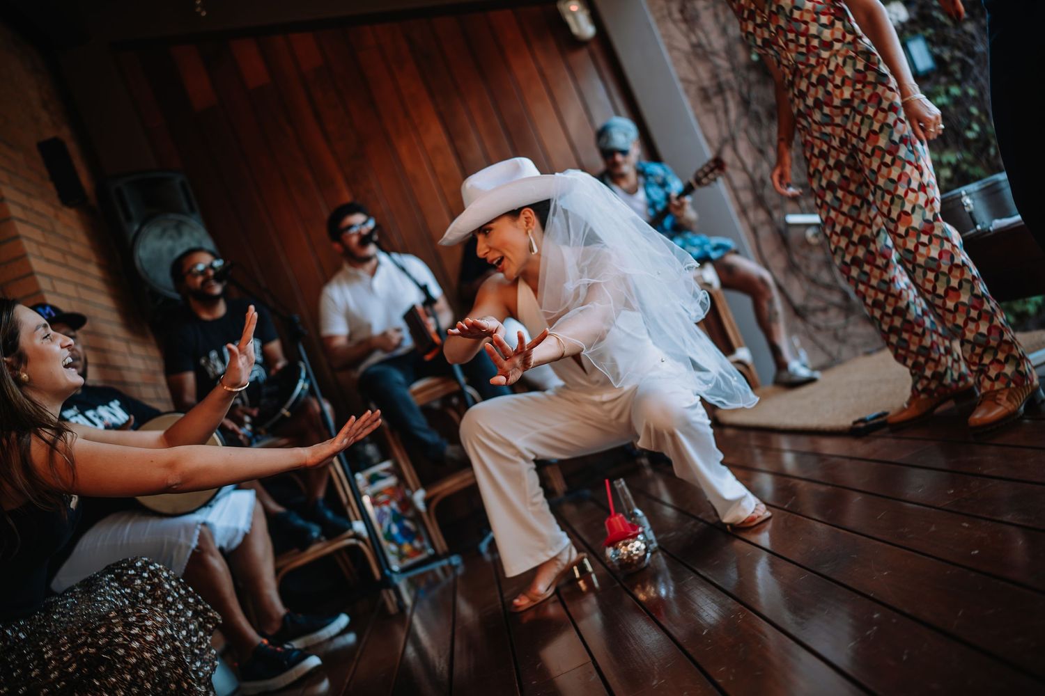 Guests enjoying lively dance party on wooden deck during daytime celebration.