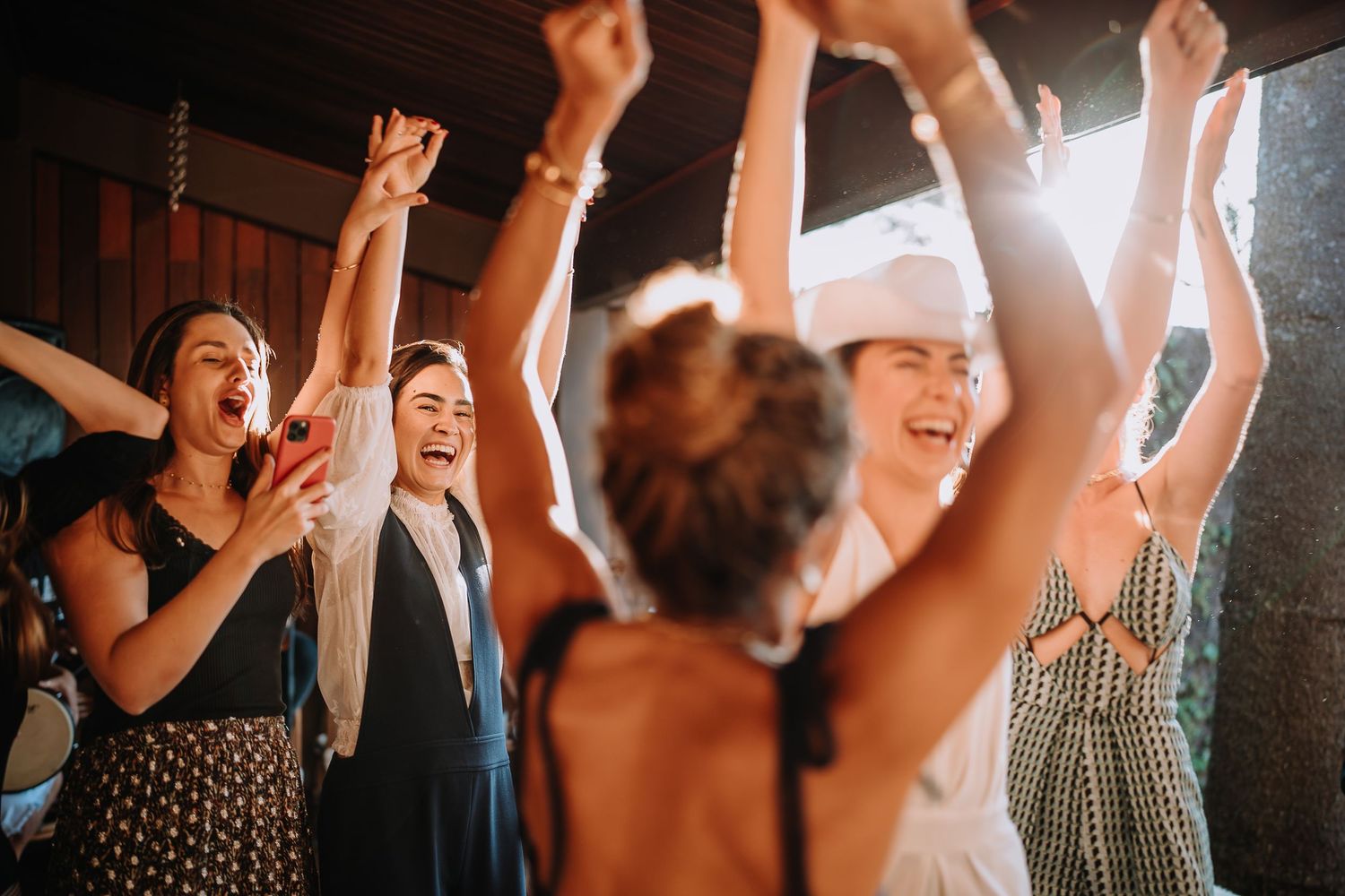Crowd raises their hands in celebration at a joyful indoor event.