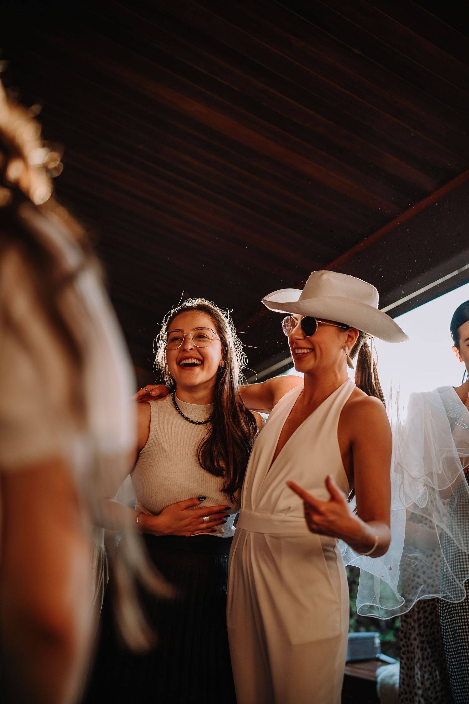 People in white outfits share laughs during an indoor celebration.