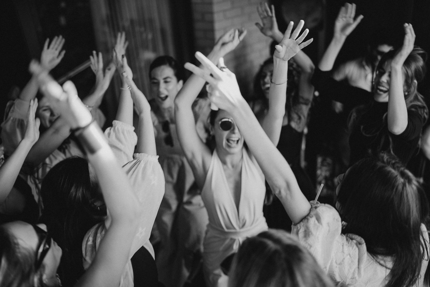Dark silhouettes of hands raised in the air during an energetic party.