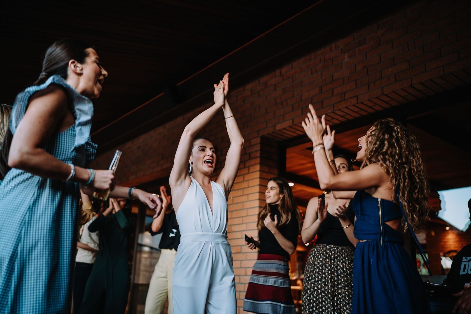 Party attendees in blue and white outfits dance at an indoor celebration.