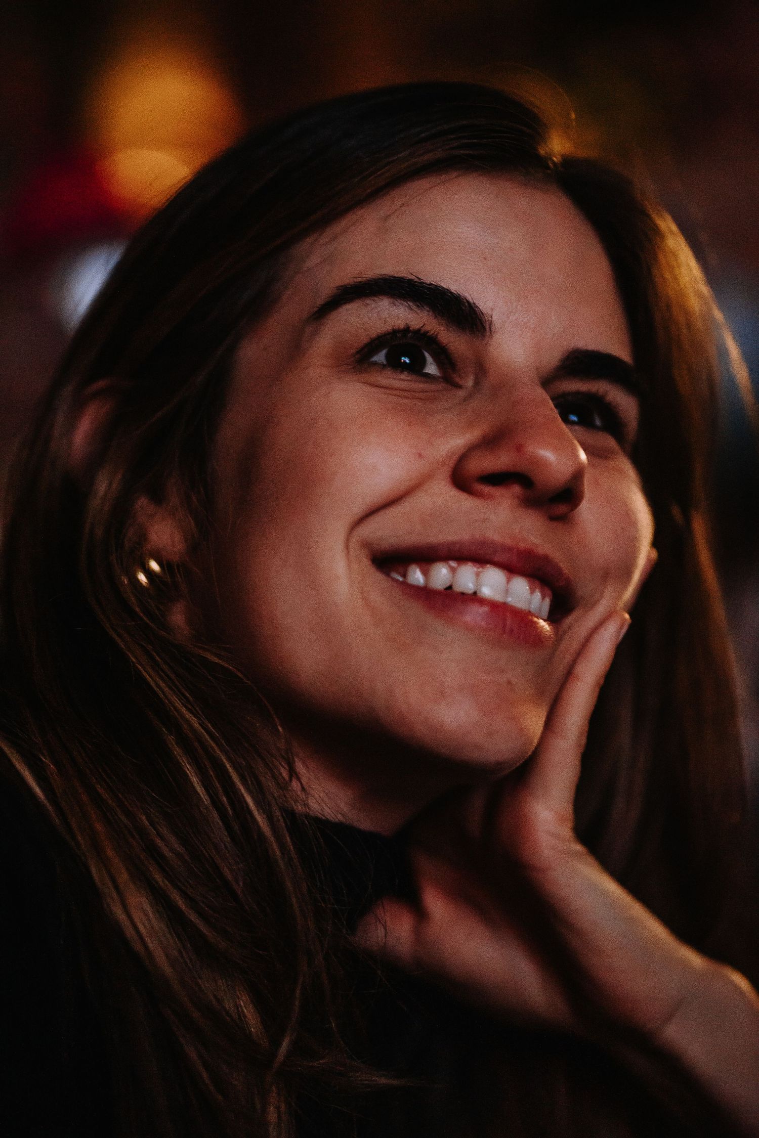 Close-up shot of a person smiling in warm, dramatic lighting.