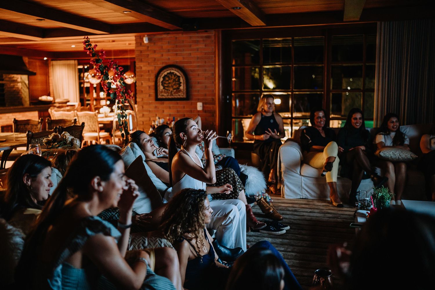 A dimly lit venue with an audience watching an evening performance in a cozy wooden interior.
