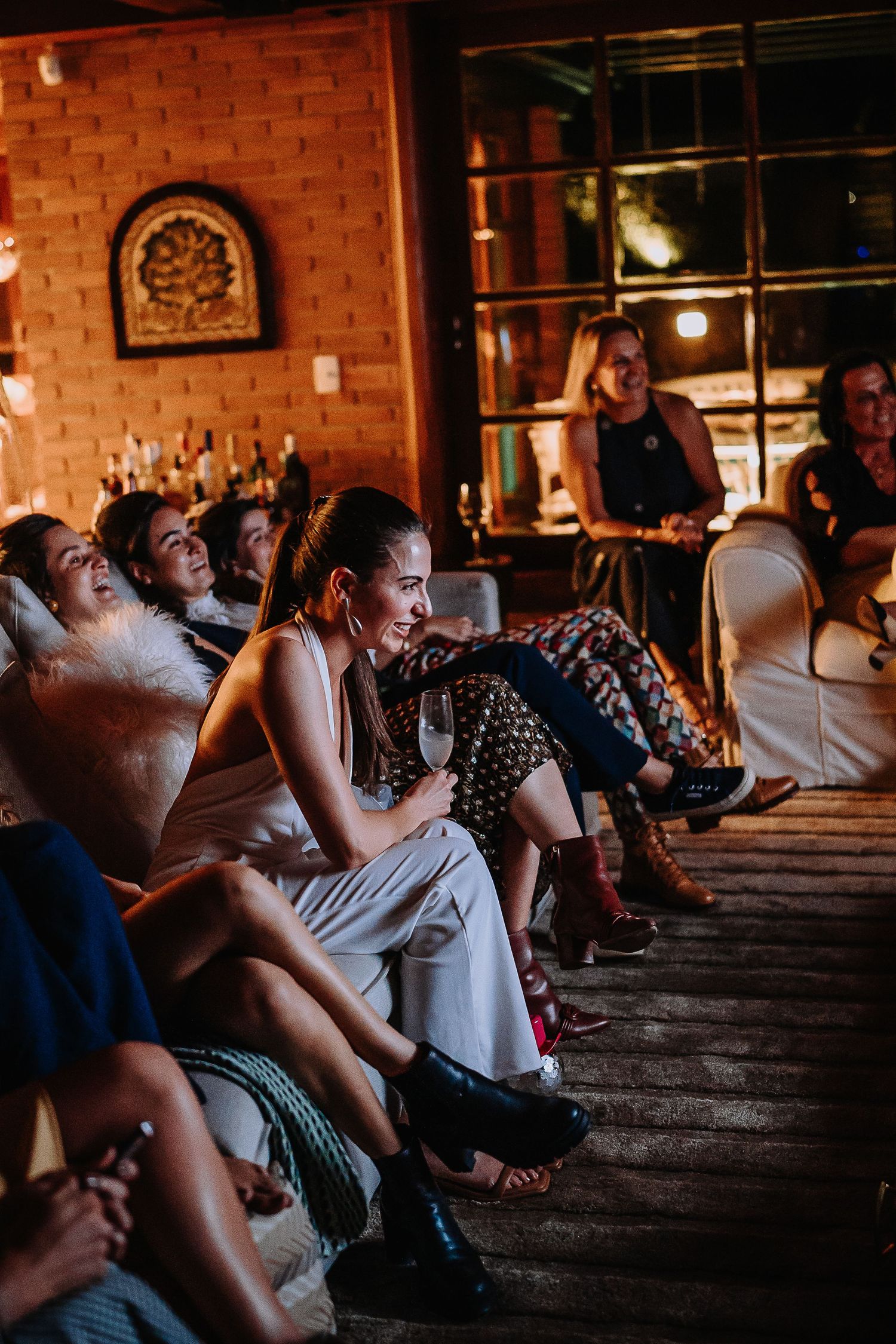 People seated in rows watching intently in a rustic venue with brick walls and ambient lighting.